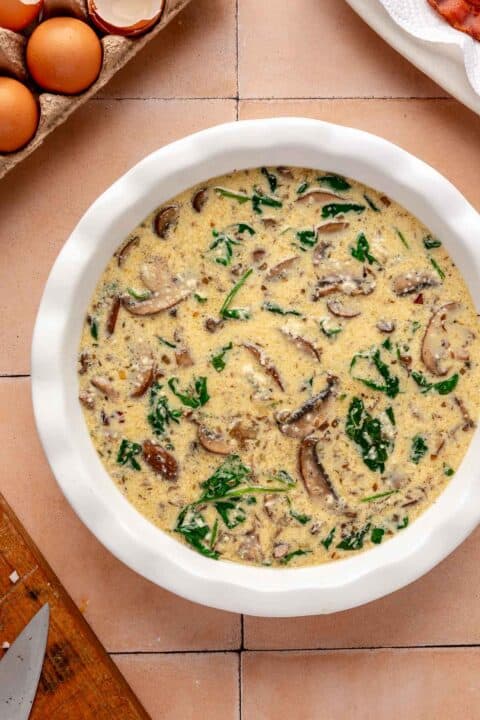 egg and mushroom spinach mixture added to a white baking dish