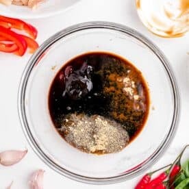 soy sauce, oyster sauce, fish sauce, brown sugar, pepper, and ginger in a clear bowl