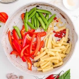 snow peas, red bell peppers, garlic, thai chilies, and corn is added to a nonstick skillet