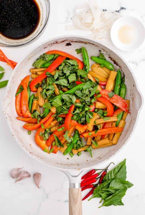fresh thai basil and green onions are added to the nonstick skillet along with other vegetables