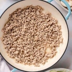 ground pork broken into smaller pieces in an enameled cast iron skillet