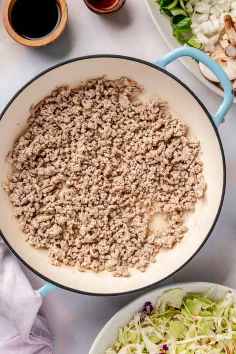 ground pork broken into smaller pieces in an enameled cast iron skillet
