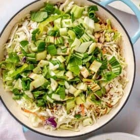 bok choy and cabbage mixture added in an enameled cast iron skillet