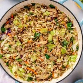 soy sauce added to cooked down cabbage and bok choy in an enameled cast iron skillet