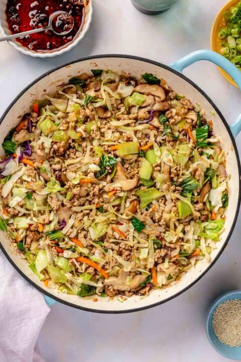 soy sauce added to cooked down cabbage and bok choy in an enameled cast iron skillet