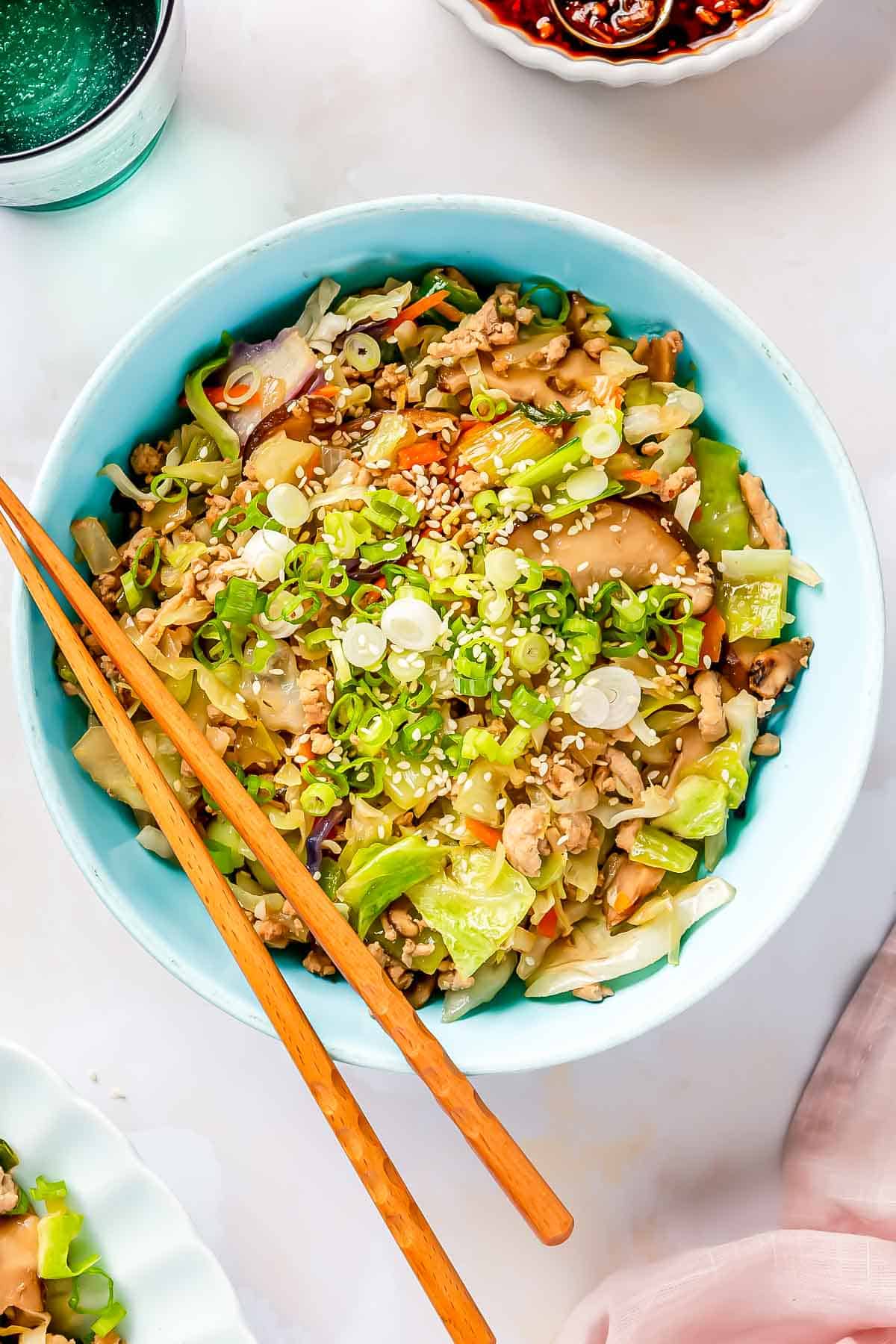 eggroll filling in a blue bowl with wooden chopsticks laying on top