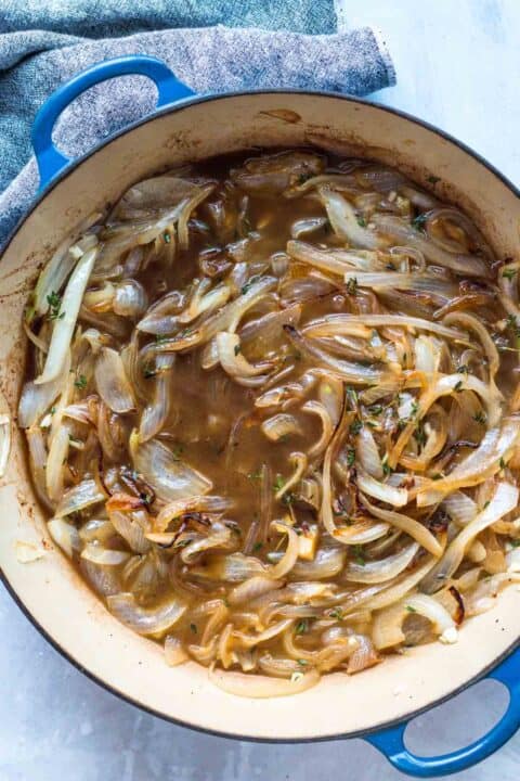 beef broth and fresh thyme has been added to the caramelized onions in the dutch oven