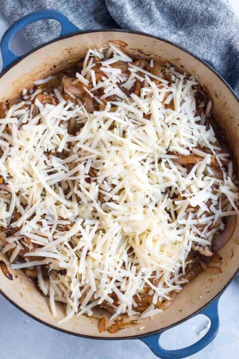 shredded gruyere cheese on top of chicken and onions