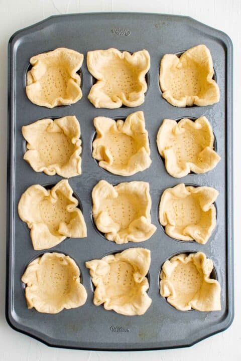 crescent dough pressed into a 12 cup metal muffin tin