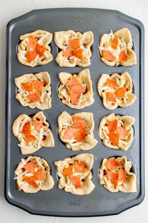 crescent dough in muffin cups are filled with pepperoni pizza toppings