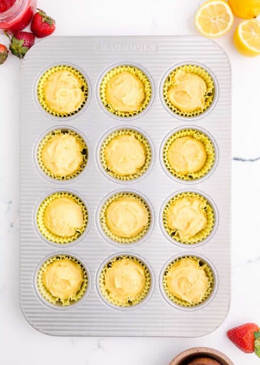 cupcake batter filled in yellow cupcake liners in a metal muffin pan