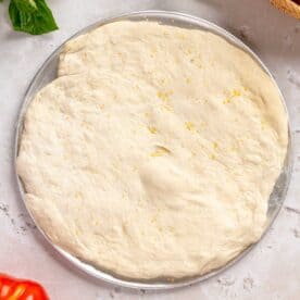 pizza dough formed into a circle on a metal pizza pan