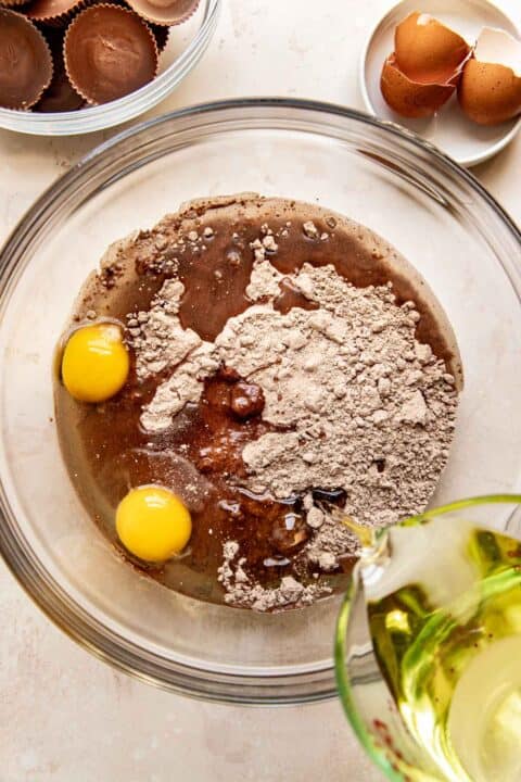 oil and eggs added to a clear bowl with brownie mix