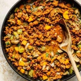 chorizo and vegetables simmering in a nonstick skillet with a wooden spoon