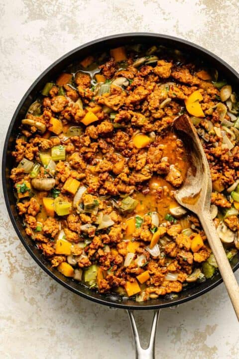 chorizo and vegetables simmering in a nonstick skillet with a wooden spoon