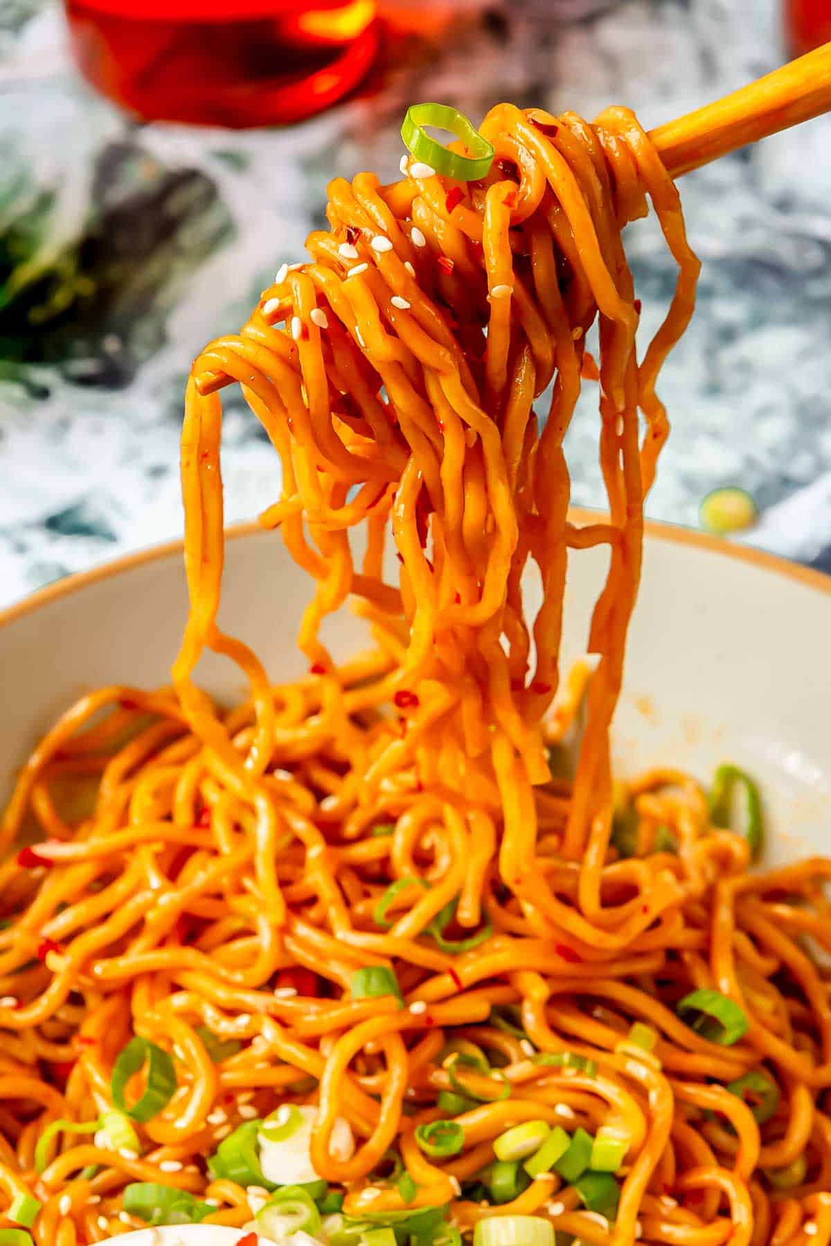 a pair of chopsticks is lifting sesame ramen out of a bowl