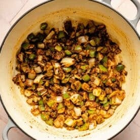 green bell peppers, onions, and seasonings mixed in a dutch oven