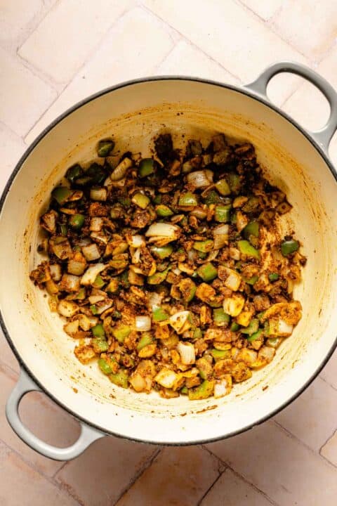 green bell peppers, onions, and seasonings mixed in a dutch oven