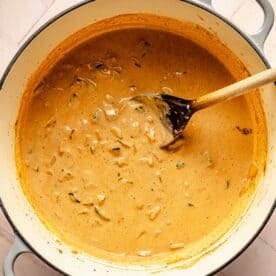 a wooden spoon is in the center of a dutch oven with the chili mixture being stirred