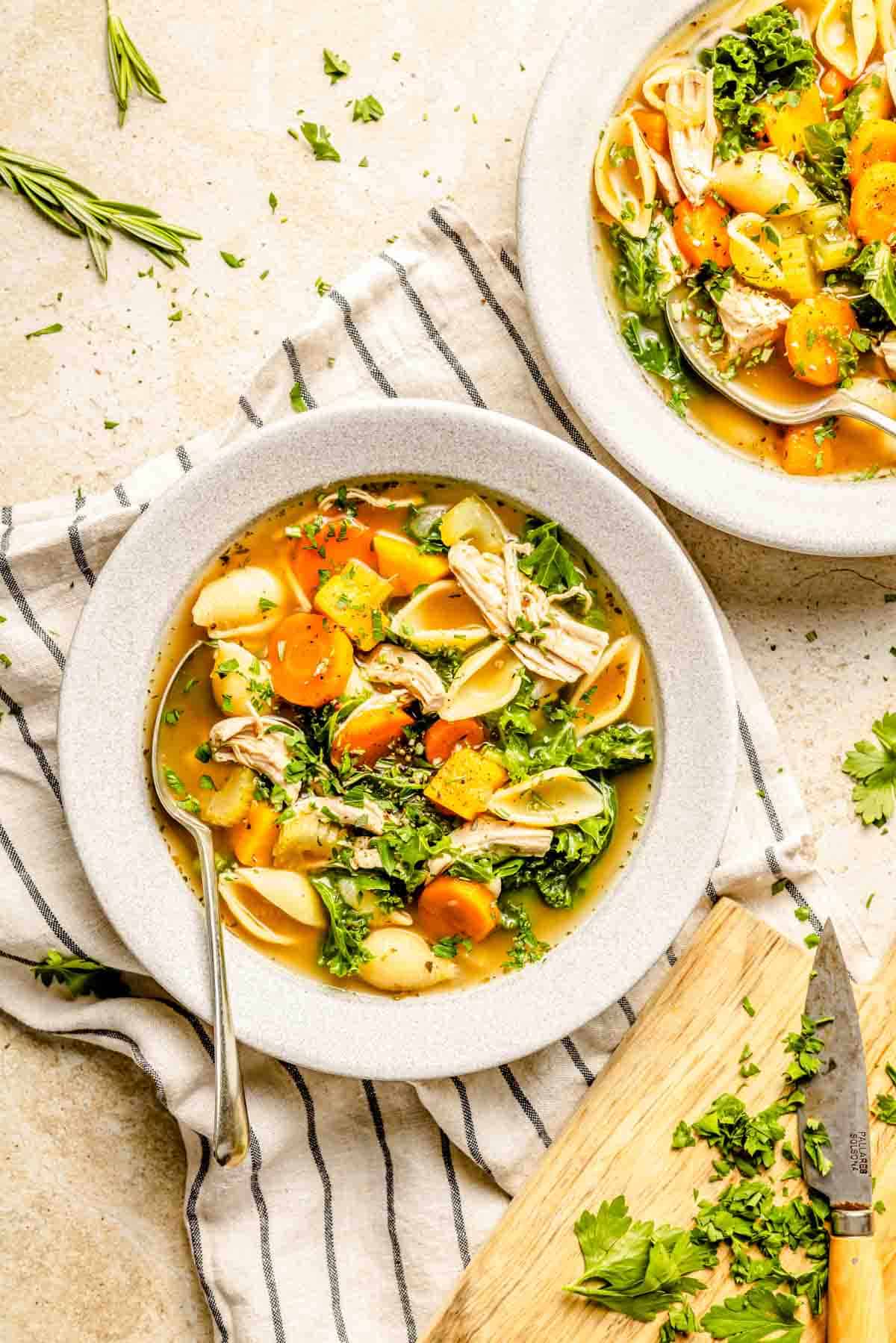 a bowl of turkey vegetable soup in a grey bowl with fresh parsley sprinkled on top