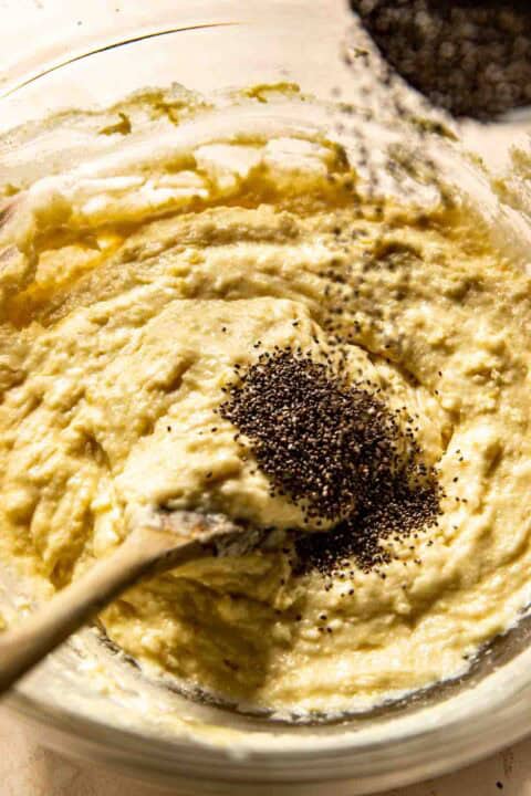 Mixing chia seeds into a bowl of batter with a wooden spoon.