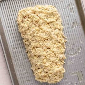 Unbaked haddock with topping on a greased metal baking sheet.