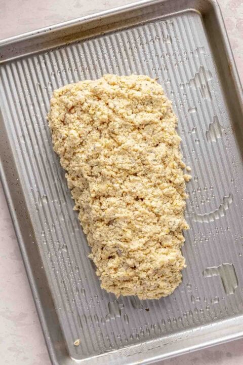 Unbaked haddock with topping on a greased metal baking sheet.