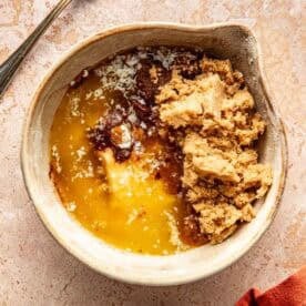 A bowl containing melted butter, brown sugar, and spices, with a fork resting nearby.